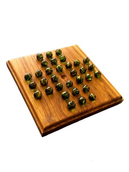 Marble Solitaire Game Played On A Wooden Board